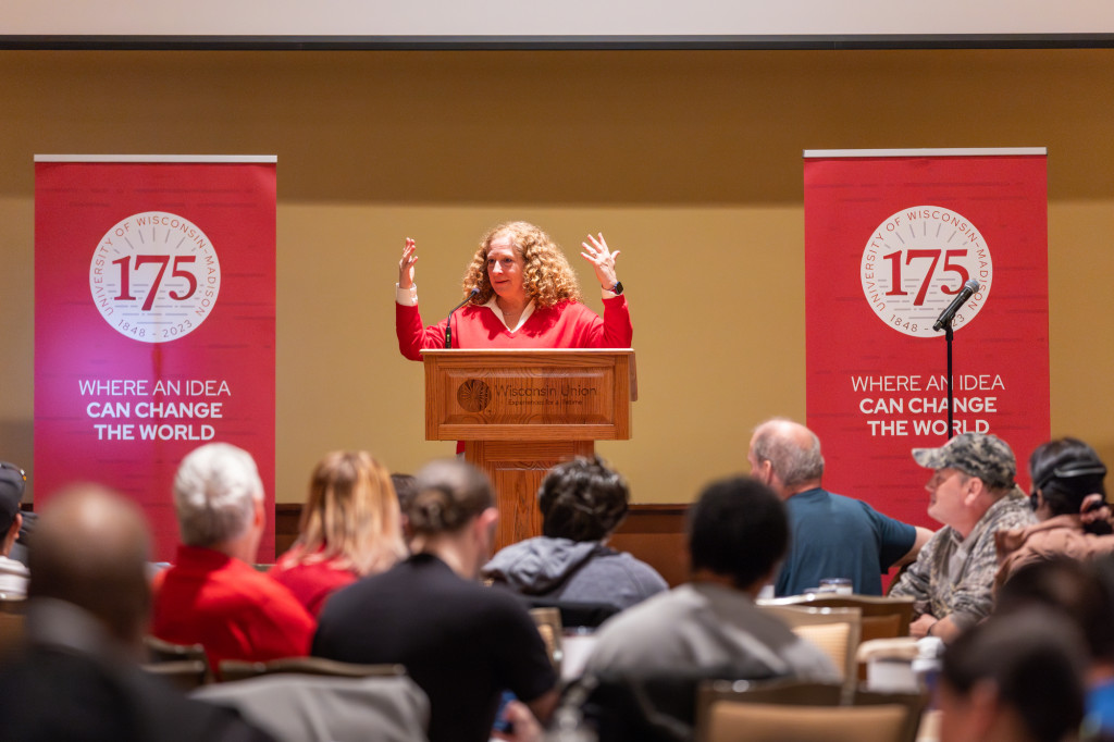 A woman gestures as she speaks at a podium.