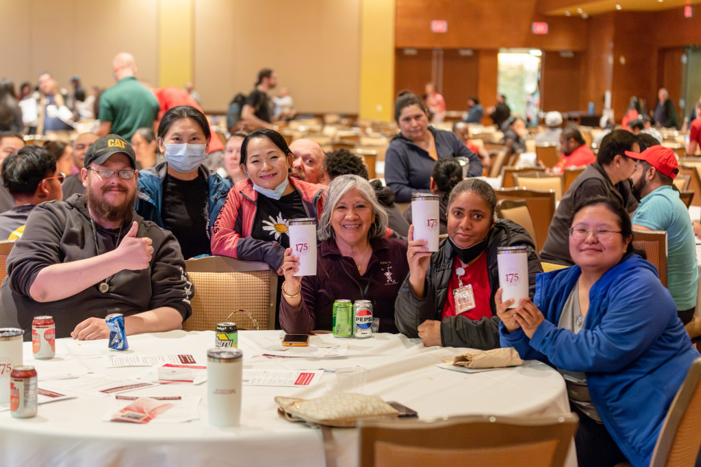 People sitting at a table hold up coffee mugs.