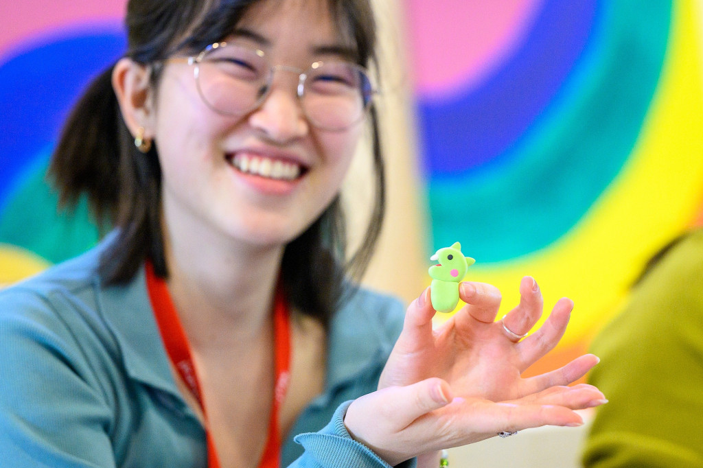 A woman smiles and holds up a tiny dragon.