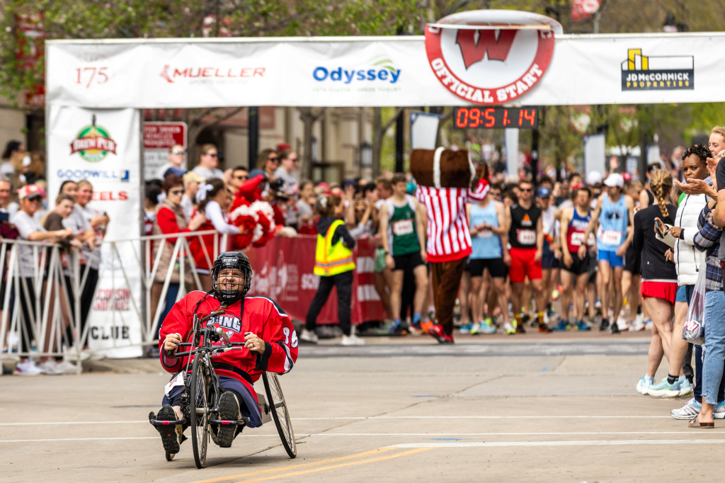 A person in a wheelchair rolls past a Crazylegs banner over the road.