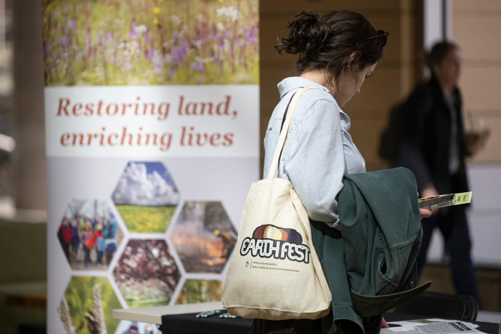 People walk by booths with Earth Fest information.