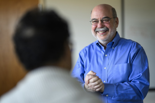 Photo of William Schwab smiling as he interacts with a colleague