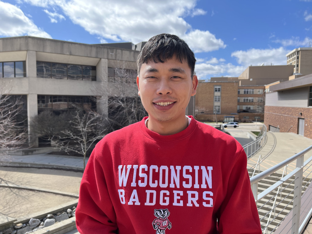 A man with a Wisconsin Badgers sweatshirt smiles at the camera.