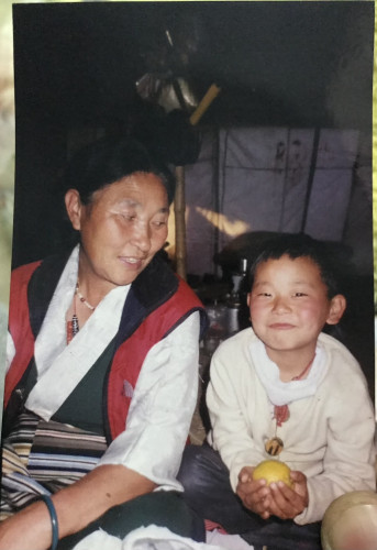 A woman smiles and looks upon a young child.