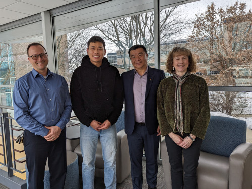 Four people stand together looking at the camera.