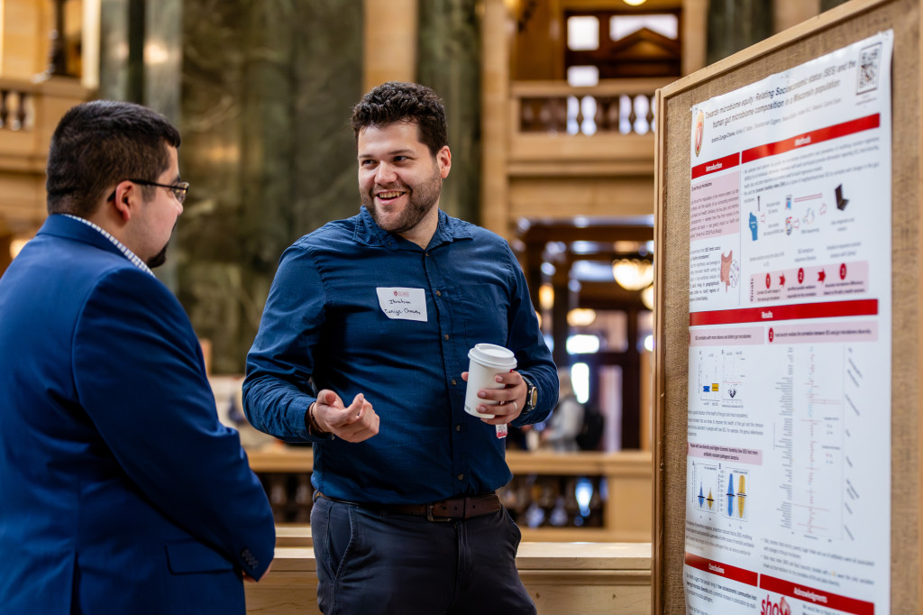 A man talks in front of a poster board.