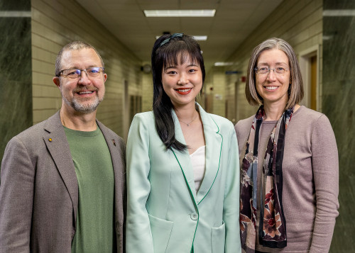 Photo of three people standing and smiling at the camera.