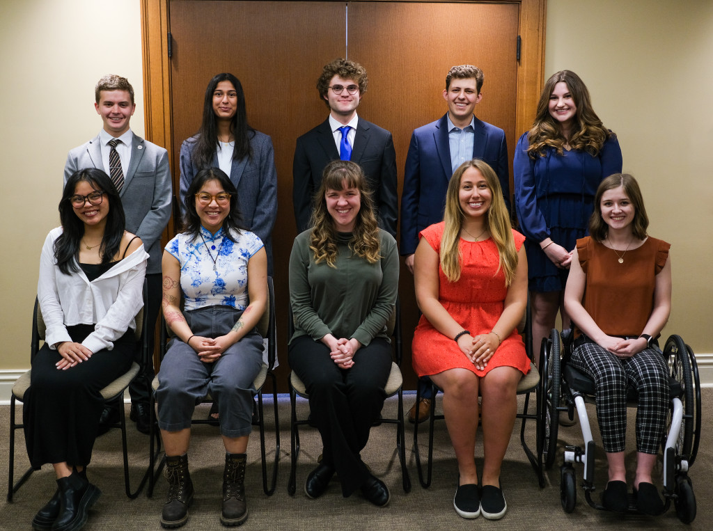 Ten people pose for the camera, five seated in the front row and five standing in the back row.