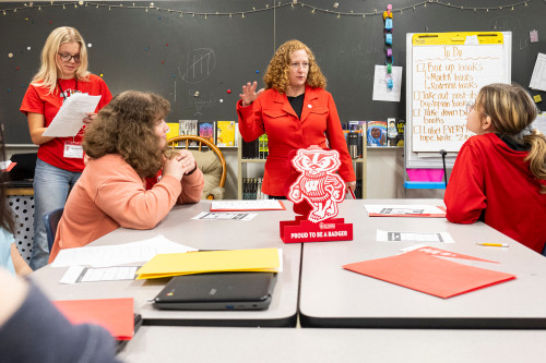 UW Chancellor Jennifer Mnookin stands at the front of a seventh-grade classroom and speaks to students seated at tables.