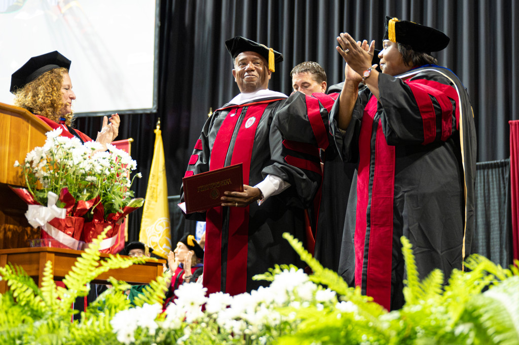A group of people in academic garb stand on a stage.