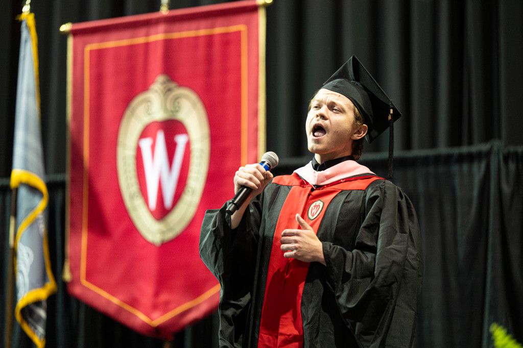 A man holds a microphone and sings.