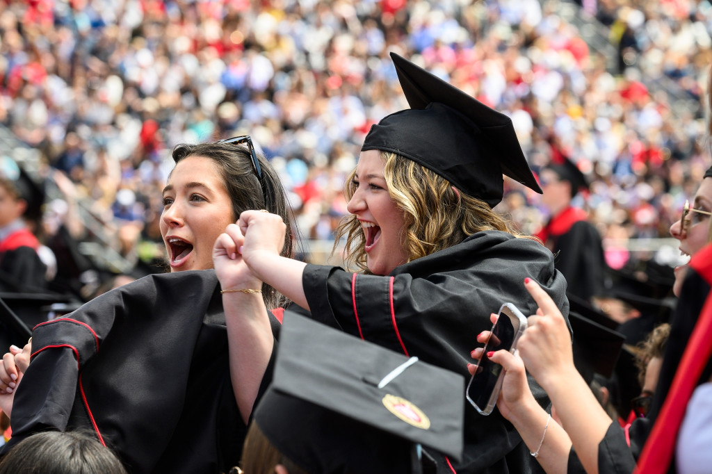 Two women in commencement garb celebrate.