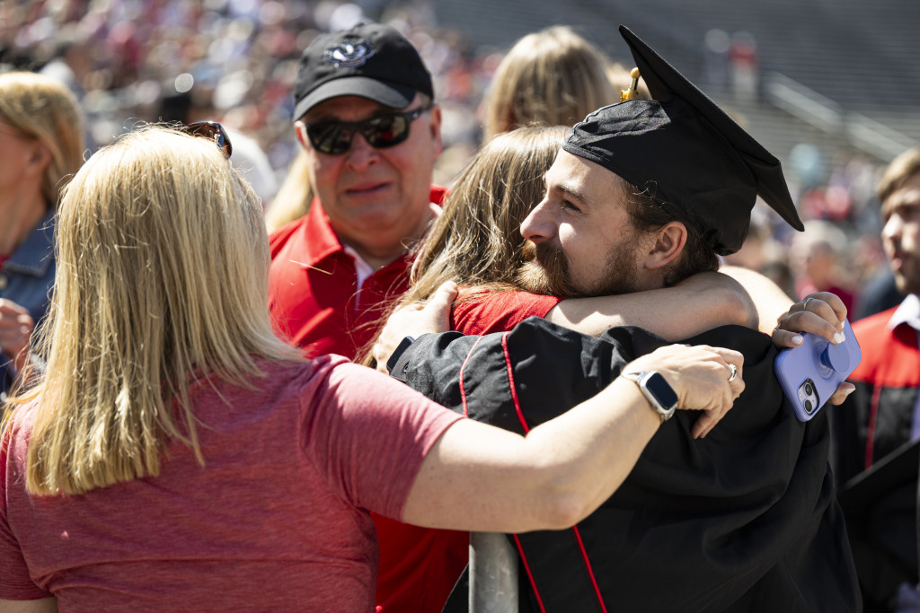 A man holds a child and embraces a woman.