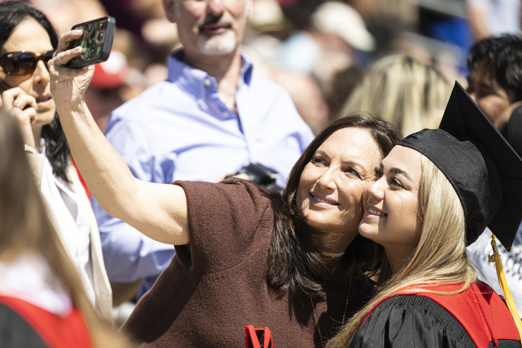 A mother and daughter smile as they take a selfie.