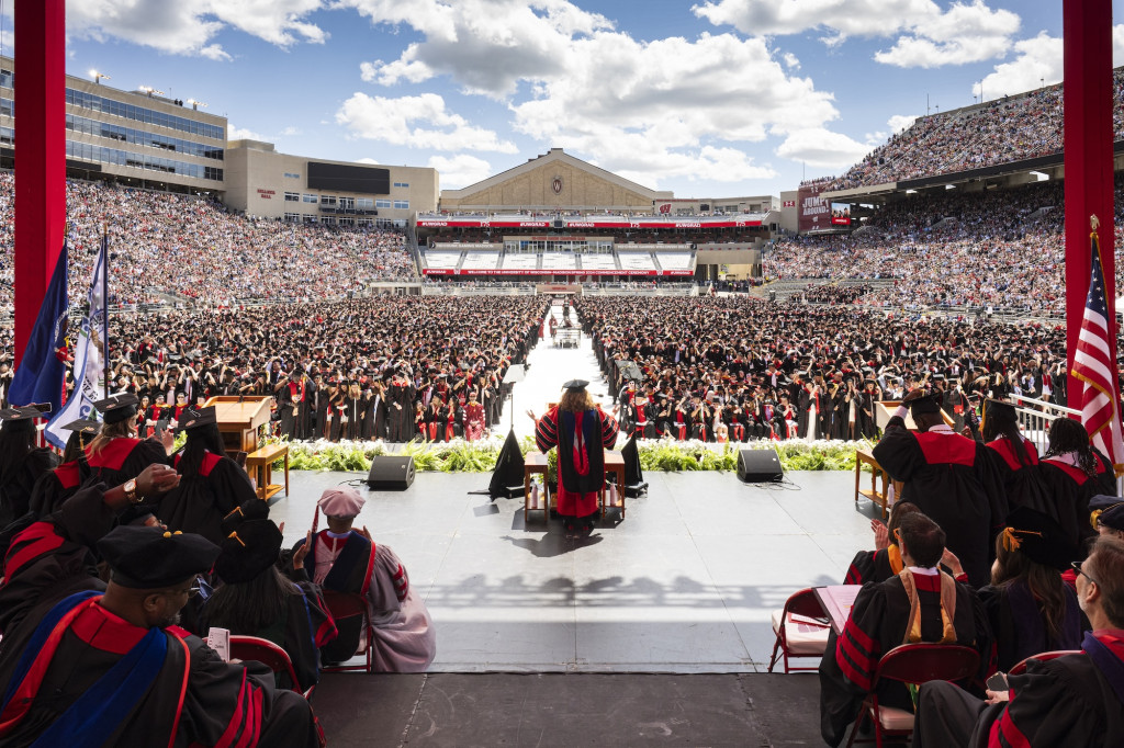 The view from behind as a woman speaks at a podium to a stadium full of people.