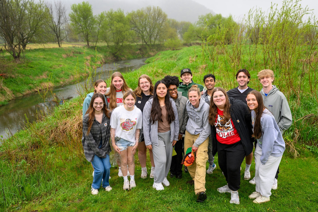 A group of people stand and pose for the camera in a green field.