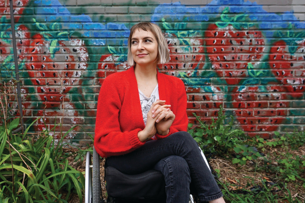 A woman in a wheelchair is shown in front of a mural.