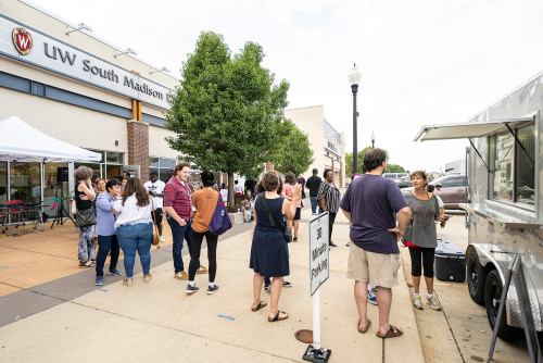 Attendees line up outside to order food from a catered food cart during a community celebration event held at the University of Wisconsin–Madison South Madison Partnership on South Park Street on Aug. 25, 2022.