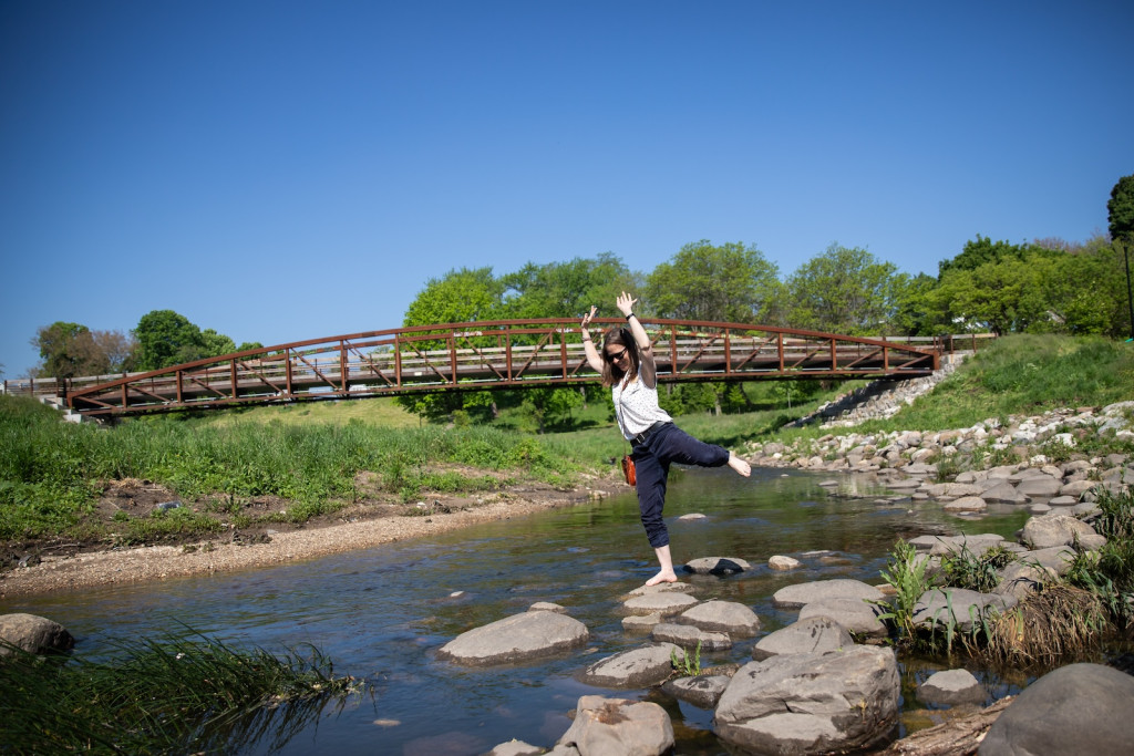 A woman dances on a rock in a river.