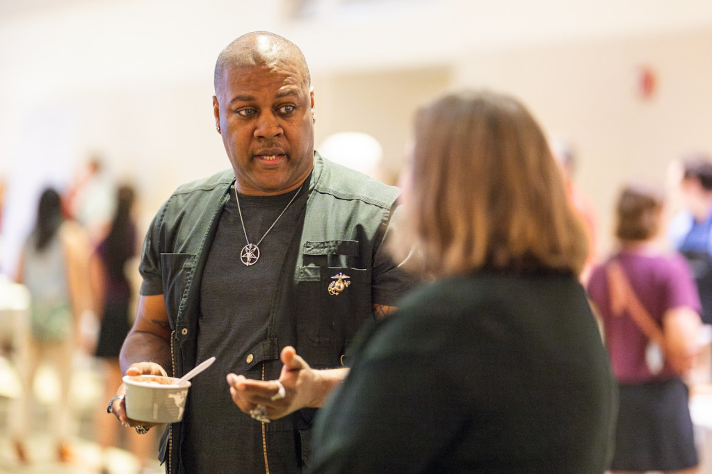 A man talks to a woman; both are holding ice cream.