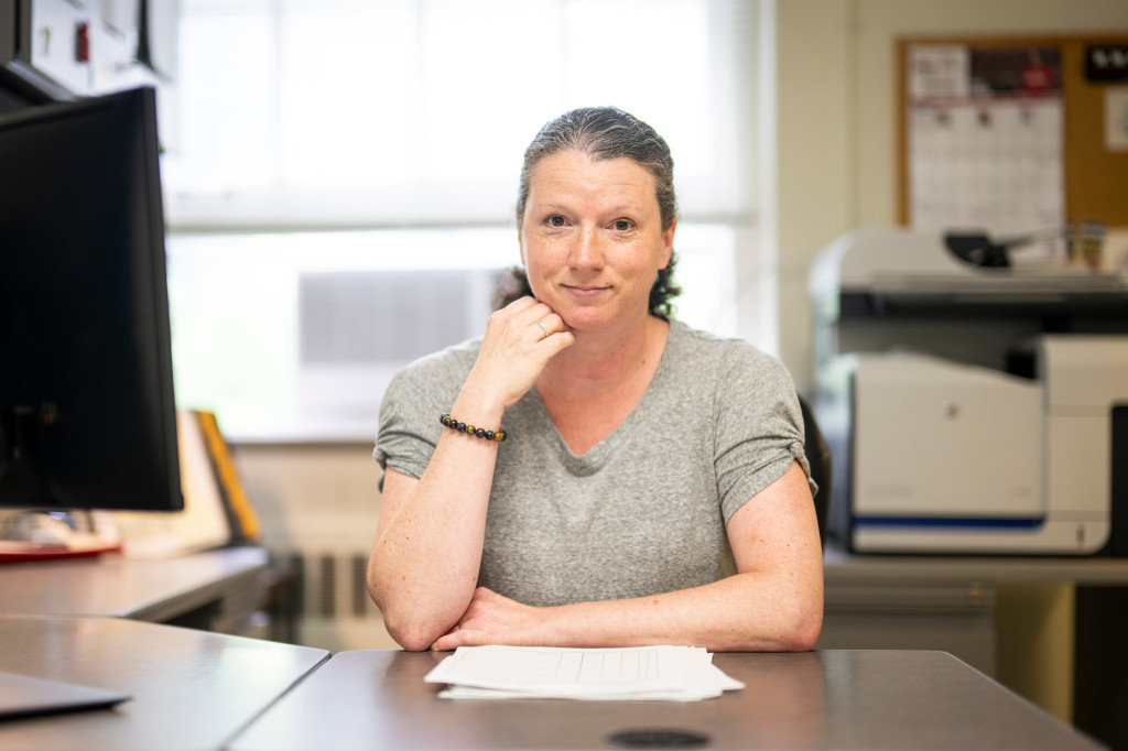 A woman sits at her desk and stares at the camera.