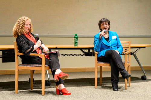 Chancellor Mnookin and NIH Director Bertagnolli sit in chairs and speak into microphones at the front of a lecture hall.