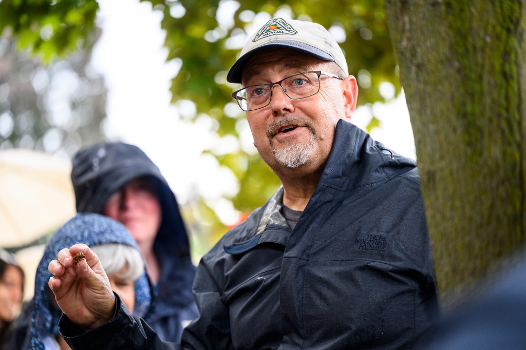 Standing outside in rain, a man speaks to a gathered audience.