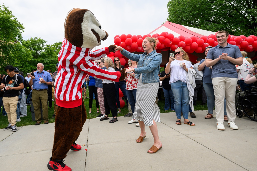 A woman dances with a person in a mascot suit.