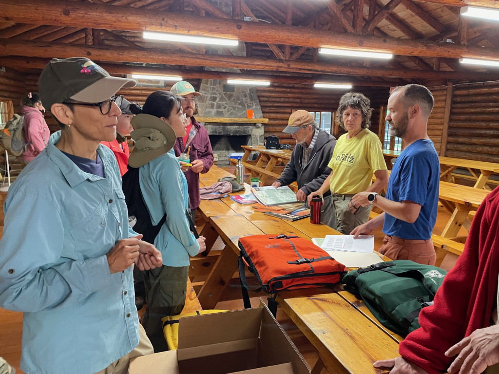 People gather around a table in a building, full of equipment.