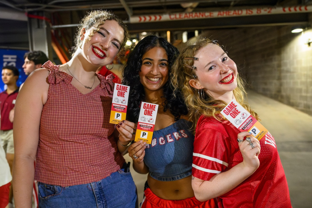 Three women smile for the camera and hold up tickets.