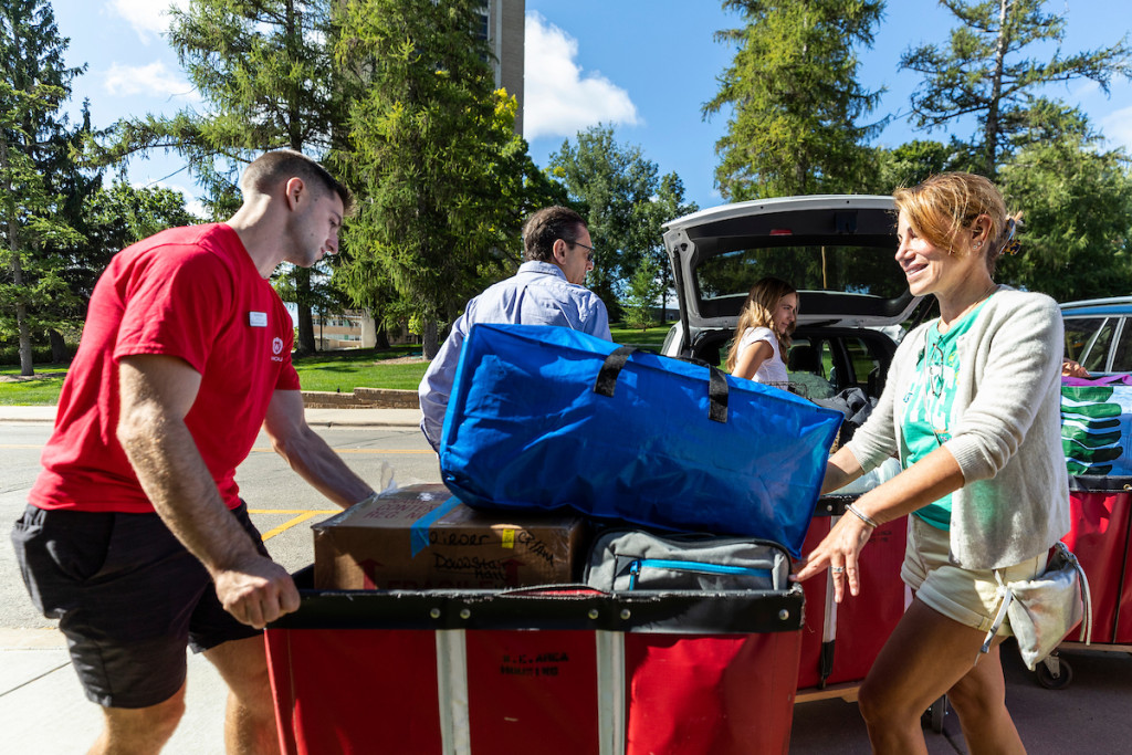 A duffel bag and other belongings are piled on a moving cart.