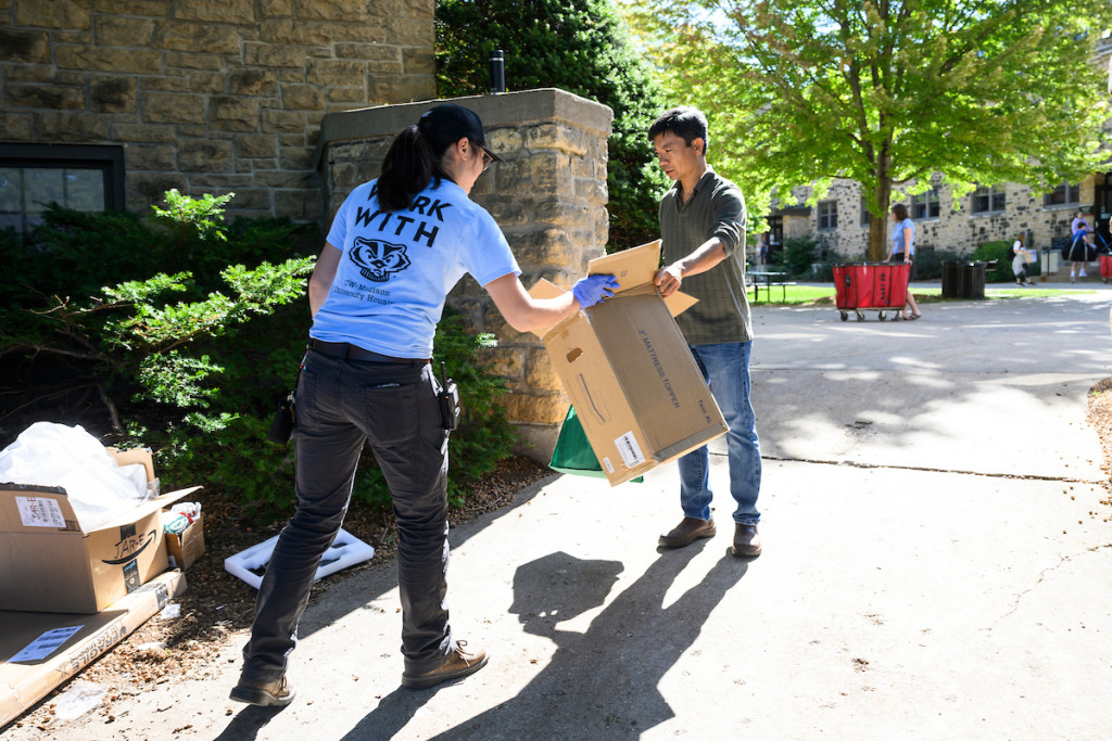 Two people break down a cardboard box.