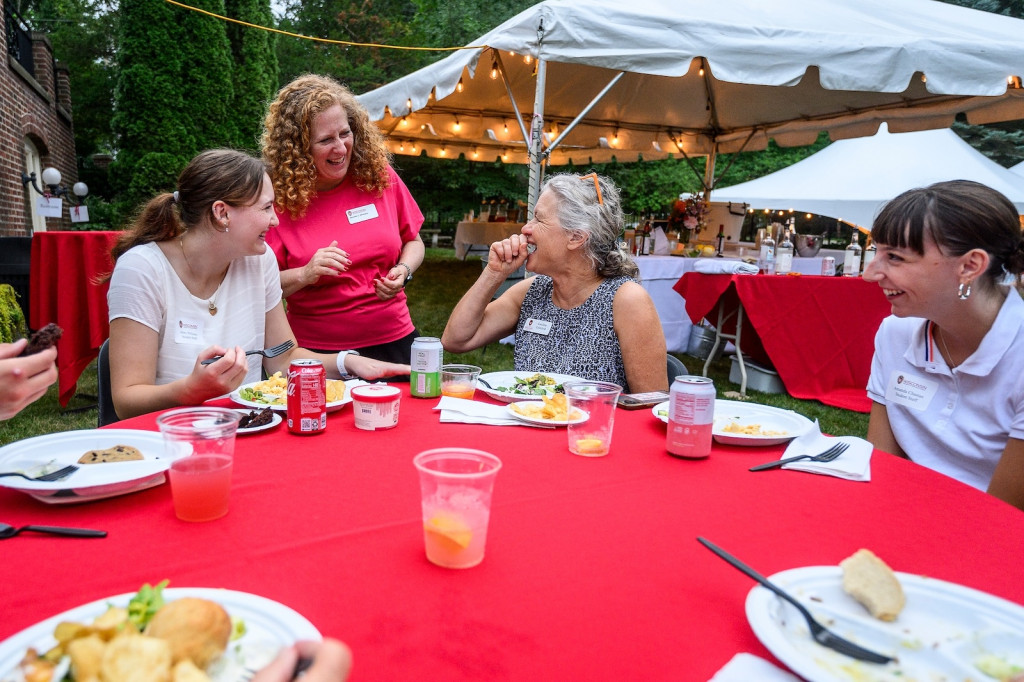 A woman speaks with three women sitting at a table.