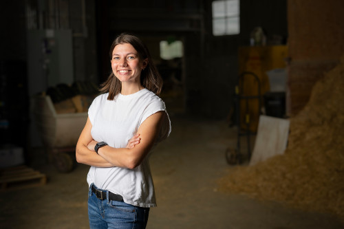 A woman stands in a barn.