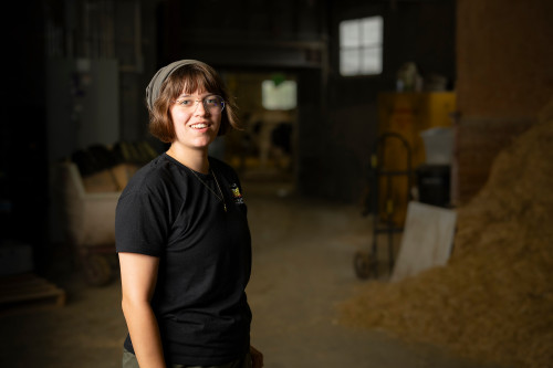 A woman stands in a barn.