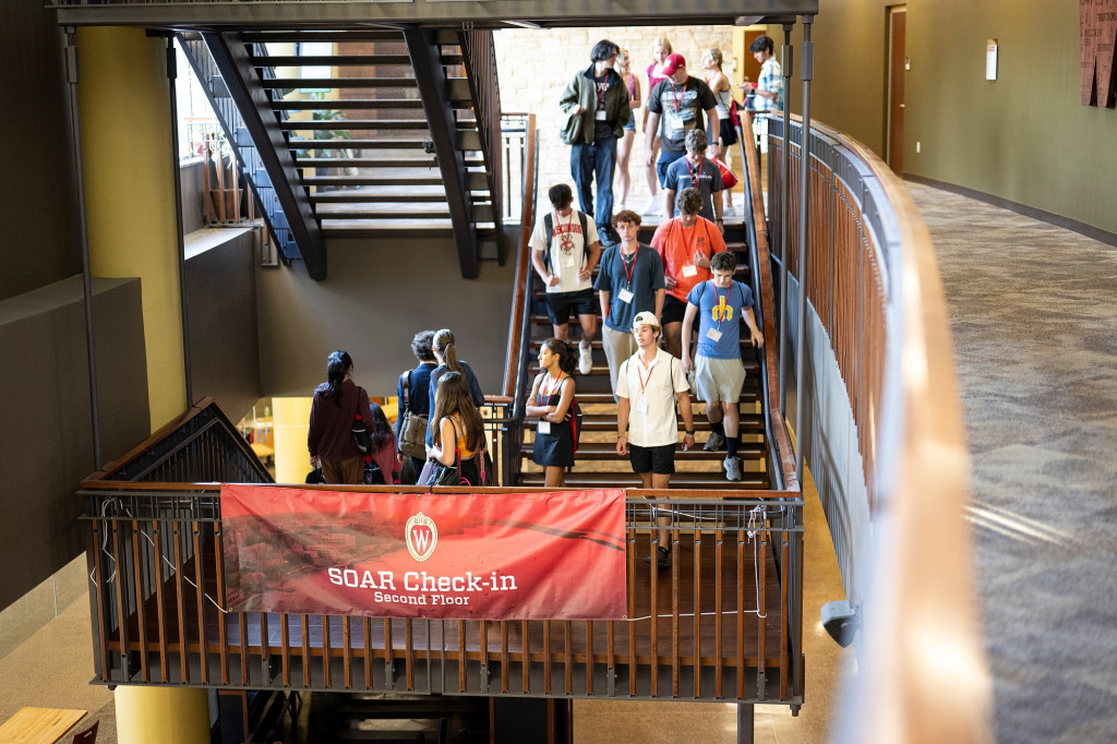 A large group of students walk down a set of stairs being illuminated by sunlight.