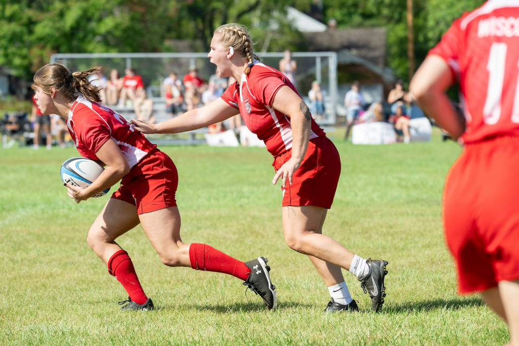 A woman pushes another woman who is running with the ball.