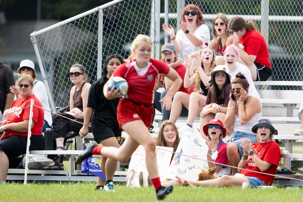 As a player runs in the foreground, fans cheer in the background.