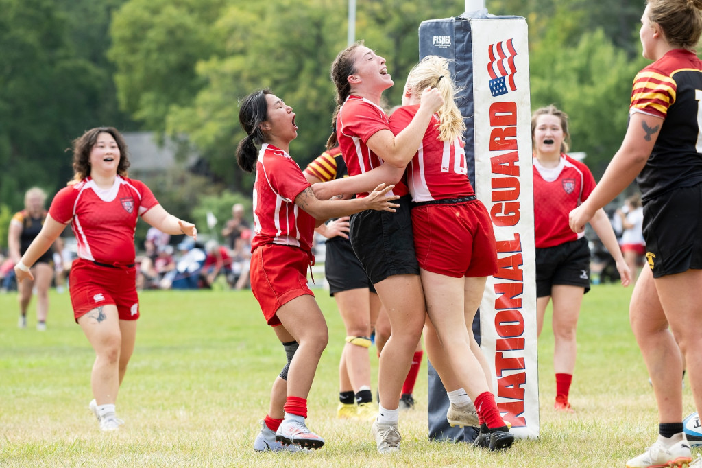 Women in red uniforms hug the woman who scored.