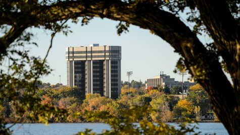 A building is shown with a lake in the foreground and a tree arching in the near foreground.