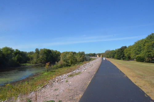 A trail cuts throw a field, with a river next to it.