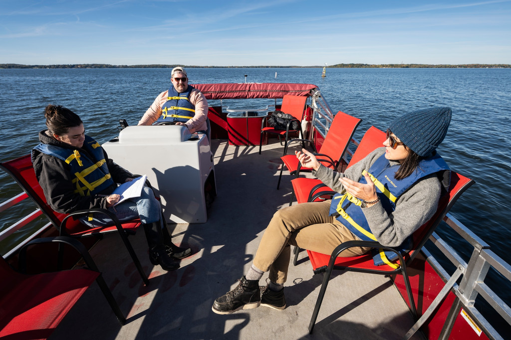 Several people sit in a pontoon boat.