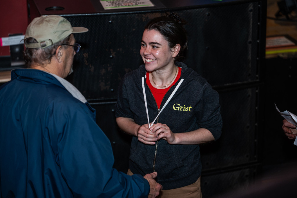 A woman talks to another person, smiling and gesturing.