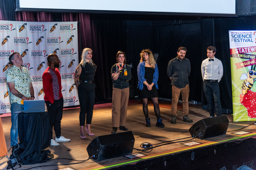 Several people stand on a stage and talk.