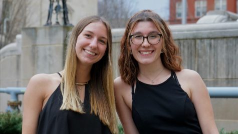 Two women sit closely together and smile for the camera.