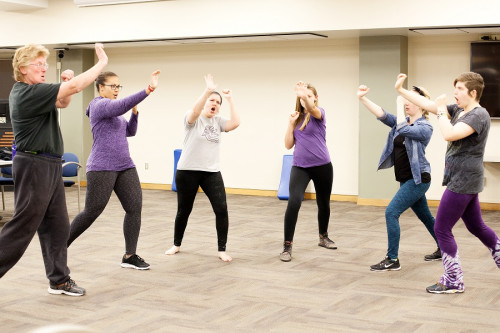 Several students stand in a room and strike aggressive fighting poses.