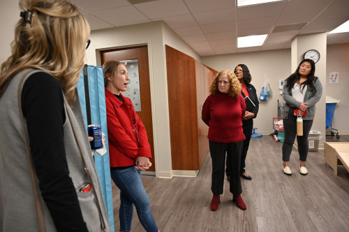 Several people stand in a hallway and talk.