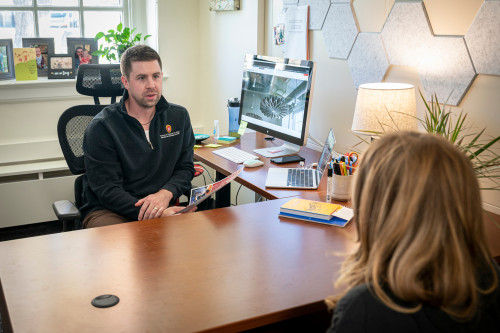 A man and a woman sit at opposite sides of a table, talking.