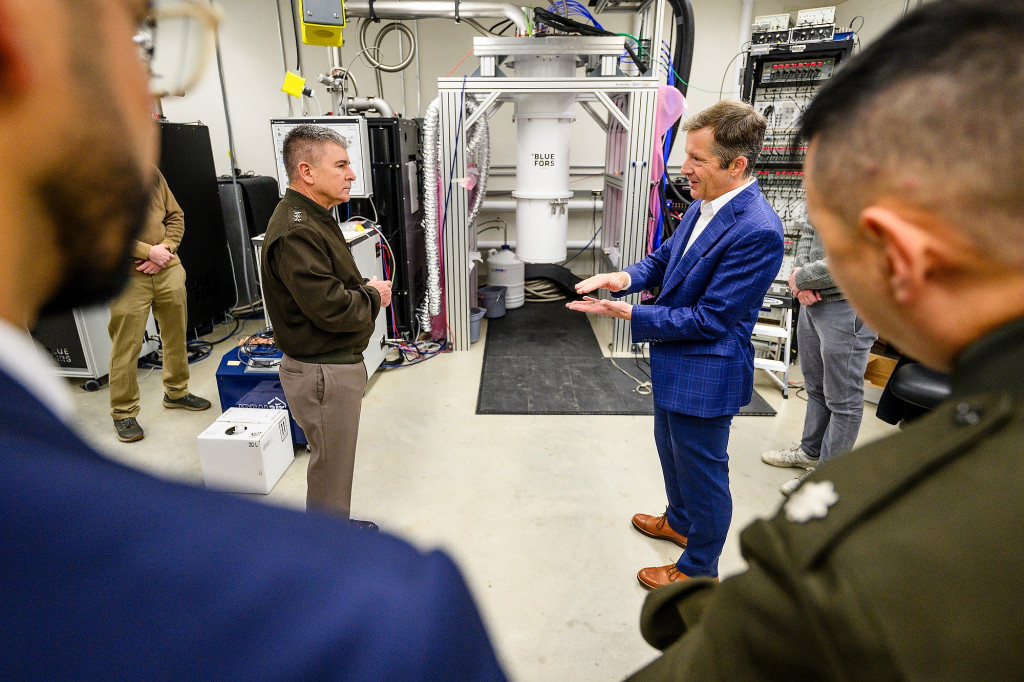 Two men speak to each other in a room full of equipment.