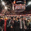 Streamers fall from the ceiling inside the Kohl Center as graduates in commencement robes smiles and dance.